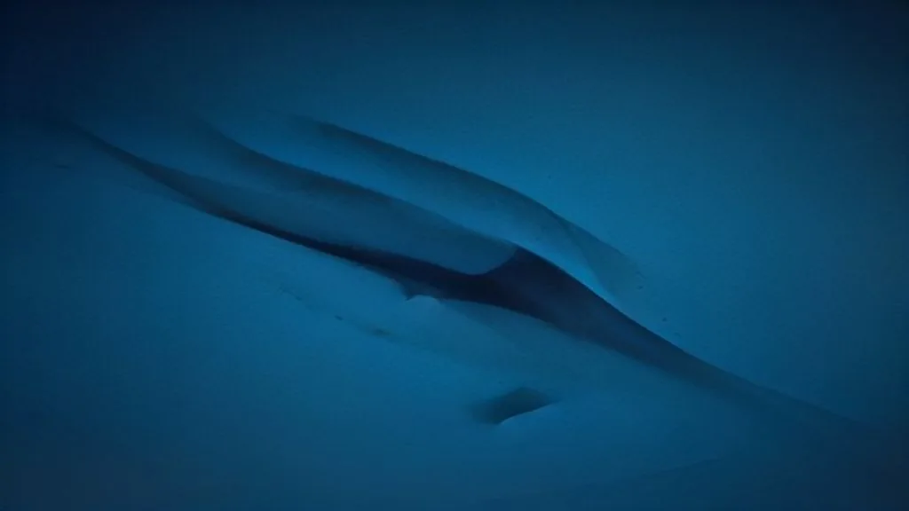 A single droplet of clear liquid frozen mid-fall against a dark background, backlit to reveal internal light refraction.