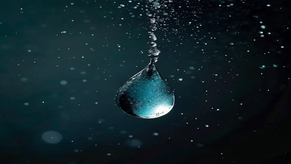 A single droplet frozen mid-fall against a dark backlit surface